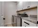Modern laundry room featuring stainless steel appliances, granite countertop, and white cabinets at 6117 Foxcroft Ave, Las Vegas, NV 89108