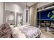 Modern primary bedroom with balcony access, plush bedding, and breathtaking city views at night at 621 Majestic Rim Dr, Henderson, NV 89012