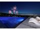 Stunning pool with lounge chairs overlooking the city skyline and fireworks display at night at 621 Majestic Rim Dr, Henderson, NV 89012