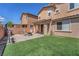Spacious backyard featuring a lush synthetic lawn, outdoor kitchen, and cozy patio seating area at 6379 Dundock Ave, Las Vegas, NV 89122