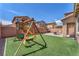 Beautiful backyard with a lush synthetic lawn, inviting patio seating area, and fun playset at 6379 Dundock Ave, Las Vegas, NV 89122