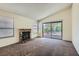 Cozy living room featuring a brick fireplace, neutral carpet, and a sliding glass door to the backyard at 6417 Plumcrest Rd, Las Vegas, NV 89108