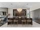 Sleek kitchen featuring a dark marble island, barstool seating, modern appliances, and elegant globe chandelier at 668 Falcon Summit Ct, Henderson, NV 89012