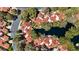 Top-down aerial shot highlighting the red tiled roofs of the homes nestled among mature trees near lake at 6925 Emerald Springs Ln, Las Vegas, NV 89113