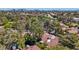 Overhead aerial view of a residential community featuring mature trees, red tiled roofs, and a distant city skyline at 6925 Emerald Springs Ln, Las Vegas, NV 89113