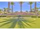 The stone entrance to Spanish Trail is beautifully landscaped with palm trees and vibrant flower beds at 6925 Emerald Springs Ln, Las Vegas, NV 89113