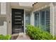 Modern front door with sleek design, complemented by green shrubbery and a welcome mat at 6925 Emerald Springs Ln, Las Vegas, NV 89113