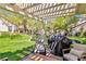Charming covered patio featuring comfortable seating and a grill, with views of the serene pond and lush landscaping at 6925 Emerald Springs Ln, Las Vegas, NV 89113