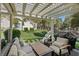 Inviting covered patio features comfortable seating, a grill, and a serene view of the lush landscaping and pond at 6925 Emerald Springs Ln, Las Vegas, NV 89113