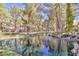 Scenic view of a tranquil pond with waterfall feature surrounded by lush greenery and mature trees at 6925 Emerald Springs Ln, Las Vegas, NV 89113