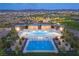 Aerial view of community pools with ample seating, picnic tables, and playground in this Gathering friendly neighborhood at 77 Tardando Ave, Henderson, NV 89015