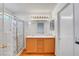 Bright bathroom featuring a double vanity, wood cabinets, and a shower with glass doors at 7721 Sour Gum Ct, Las Vegas, NV 89131
