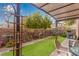 A beautifully landscaped backyard with artificial grass, potted plants, and a charming covered patio area at 7769 Peaceful Trellis Dr, Las Vegas, NV 89179
