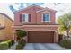 Two-story stucco home featuring a two-car garage, manicured landscaping, and a charming, covered front entry at 7769 Peaceful Trellis Dr, Las Vegas, NV 89179