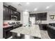 Modern kitchen featuring stainless steel appliances, granite countertops, dark cabinets, and an open design at 7769 Peaceful Trellis Dr, Las Vegas, NV 89179