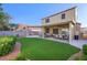 Well-maintained backyard with artificial grass, a covered patio, and lush landscaping at 7916 Nesting Pine Pl, Las Vegas, NV 89143