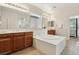 Well-lit bathroom featuring double vanities, soaking tub with white surround, and neutral color scheme at 8316 Imperial Lakes St, Las Vegas, NV 89131