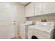 Functional laundry room with a washer, dryer, storage cabinets and an entry door at 8316 Imperial Lakes St, Las Vegas, NV 89131