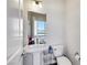 Modern powder room with pedestal sink, toilet, and bright window at 9045 Knots Estate St, Las Vegas, NV 89139