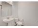 Clean half bathroom featuring a pedestal sink, toilet, and white walls for a minimalist aesthetic at 985 Via Lombardi Ave, Henderson, NV 89011