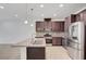 Modern kitchen with stainless steel appliances, a granite island, and stylish dark wood cabinets at 985 Via Lombardi Ave, Henderson, NV 89011