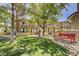 Charming townhome exterior with manicured lawn, mature trees, and community bench seating at 9901 Trailwood Dr # 2109, Las Vegas, NV 89134