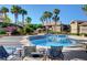 Community pool area with inviting blue water, lounge chairs, palm trees, and beautiful landscaping at 9901 Trailwood Dr # 2109, Las Vegas, NV 89134