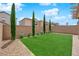 Private backyard with well-manicured turf, brick walls, columnar trees, and decorative string lights at 10029 Cluny Ave, Las Vegas, NV 89178