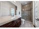 Bathroom featuring a wood vanity, light countertops, decorative mirror, and a glass enclosed shower with tile surround at 10084 Terrastone Dr, Las Vegas, NV 89148