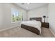 Bedroom with a large window with shutters, neutral carpet and walls, and a dark wooden bed frame and side table at 10084 Terrastone Dr, Las Vegas, NV 89148