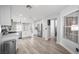 Open-concept kitchen featuring stainless steel appliances, white cabinets, and wood-look flooring at 10244 Amber Hue Ln, Las Vegas, NV 89144