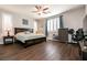 Bedroom with wood floors, ceiling fan, two windows, and furniture at 10417 Artful Stone Ave, Las Vegas, NV 89149