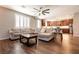 Spacious living room flows into the kitchen, highlighted by wood floors, a ceiling fan, and lots of natural light at 10417 Artful Stone Ave, Las Vegas, NV 89149
