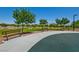 Park benches surround playground space with lush trees, and paved paths in community at 10417 Artful Stone Ave, Las Vegas, NV 89149