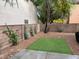 Private backyard featuring a small lawn, brick wall with shrubbery, and gravel at 10754 Balmoral St, Las Vegas, NV 89141