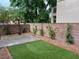 Landscaped backyard features artificial grass and a concrete patio, surrounded by a brick wall at 10754 Balmoral St, Las Vegas, NV 89141