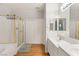 Bright bathroom featuring double sinks, wood floor, and a tiled shower with glass door at 10754 Balmoral St, Las Vegas, NV 89141