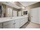 Bathroom featuring double sinks, white cabinets, and a large mirror, with shower and towel rack at 1424 Pin Cushion Rdg, Mesquite, NV 89034