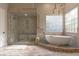 Luxurious bathroom with a stone shower, freestanding tub, and glass block window at 17 Grand Corniche Dr, Henderson, NV 89011
