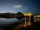 Tranquil lake view at night, framed by illuminated palm trees and distant mountain silhouettes, with pathway at 20 Via Mantova # 306, Henderson, NV 89011