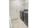 Well-lit laundry room featuring modern washer and dryer units with tiled floor and metal rack shelving at 2444 Padulle Pl, Henderson, NV 89044