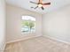 A sunlit bedroom with neutral walls, a window, plush carpet, and a ceiling fan at 2500 S Zephyr Ave, Pahrump, NV 89048