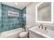 Bathroom featuring a tub with green tile surround, white vanity, and illuminated mirror at 2536 Herrod Dr, North Las Vegas, NV 89030