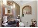 Charming powder room featuring bronze fixtures, unique vanity sink, decorative mirror, and neutral colored wall tiles at 2909 Sterling Cove Dr, Las Vegas, NV 89128