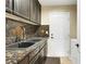 Laundry room with custom backsplash, dark cabinets, stainless sink, and a white door to the side yard at 2909 Sterling Cove Dr, Las Vegas, NV 89128