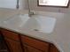 Close up of a white kitchen sink with stone countertops and wood cabinets at 3024 Nutwood St, Las Vegas, NV 89108