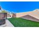 Private backyard featuring artificial grass and a brick wall under a bright blue sky at 444 Flores Cir, Las Vegas, NV 89123