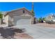 Side view of a home with a two-car garage featuring a concrete driveway and desert landscaping at 444 Flores Cir, Las Vegas, NV 89123