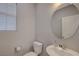 Cozy half bathroom featuring a pedestal sink and a round mirror at 5269 Silver Branch Ave, Las Vegas, NV 89118