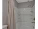 A view of the bathtub and shower combination with white tiling and neutral colored shower curtain at 5269 Silver Branch Ave, Las Vegas, NV 89118